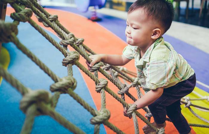 Child climbing a jungle gym at an indoor playground