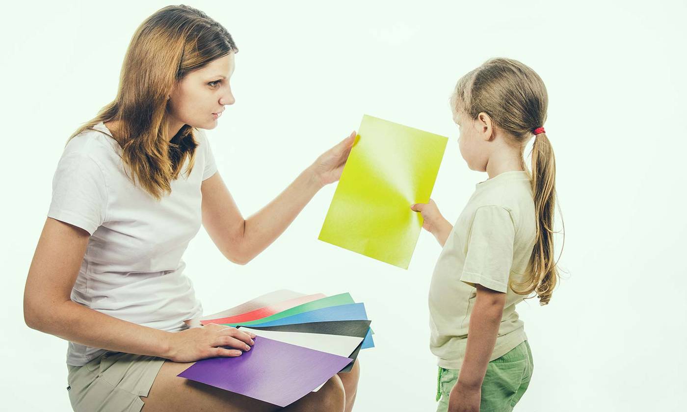 A child looking at coloured cards with an adult