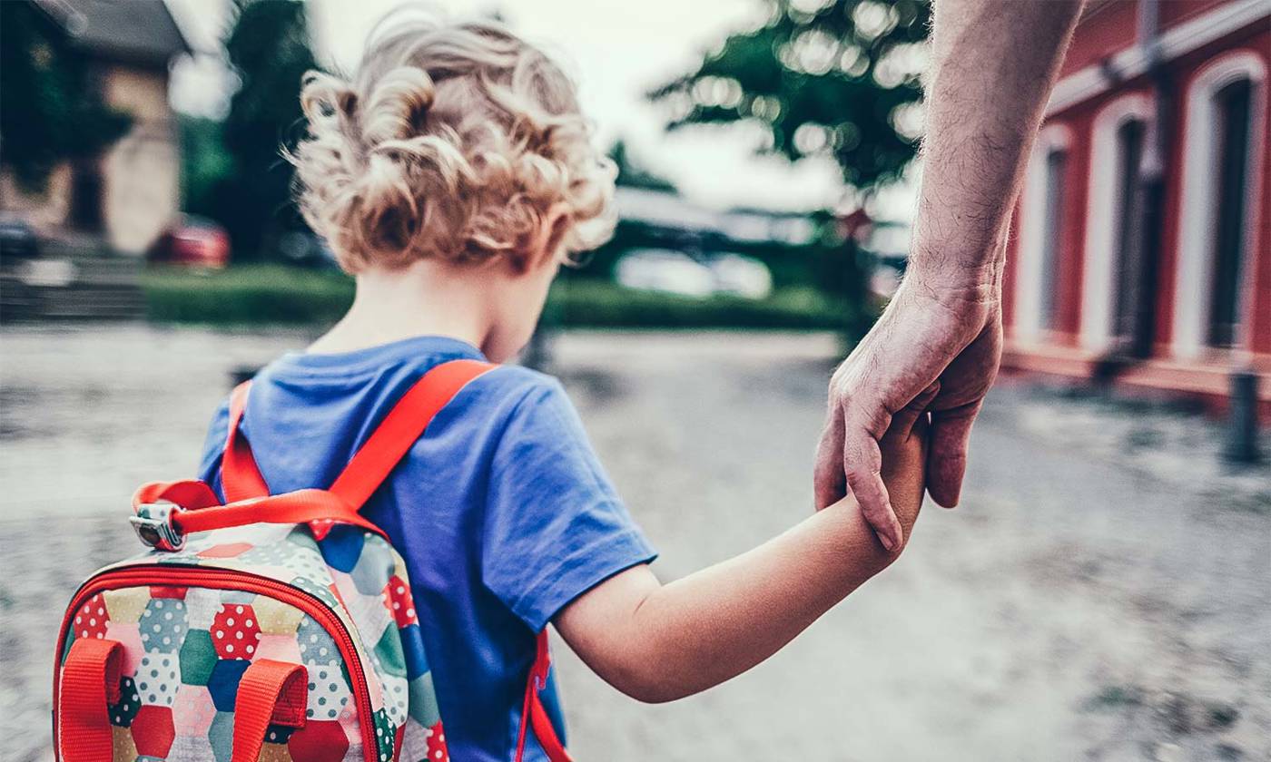 Small child with backpack holding parent's hand