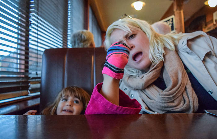 Little girl puts her socked foot on the table at a restaurant