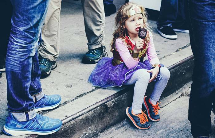Little girl sitting in the gutter eating ice-cream