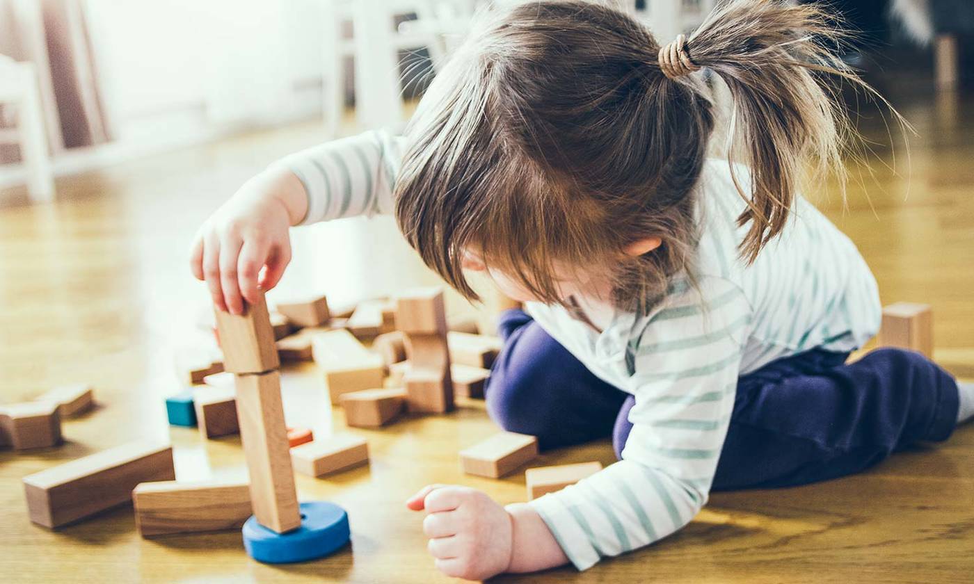 Girl building a tower of wooden blocks