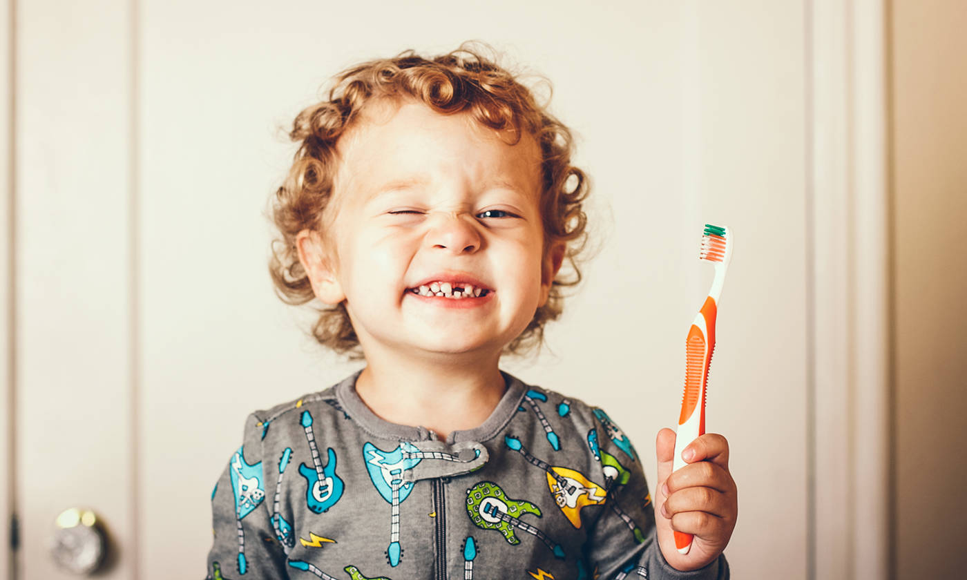 Toddler smiling while holding a toothbrush