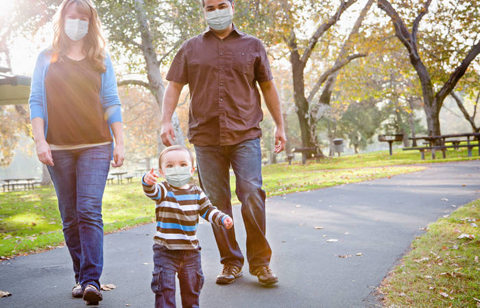 Family walking in the park wearing masks