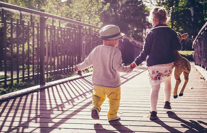 sister and little brother walking on a bridge