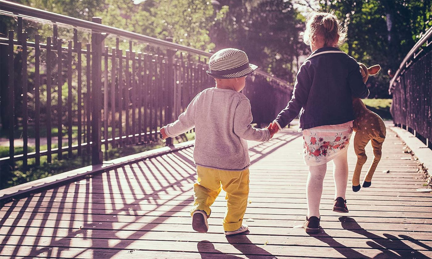 sister and little brother walking on a bridge