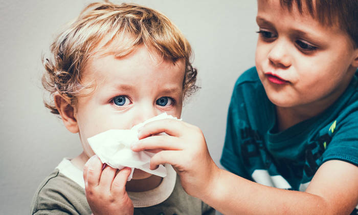 Older boy helping younger blow his nose