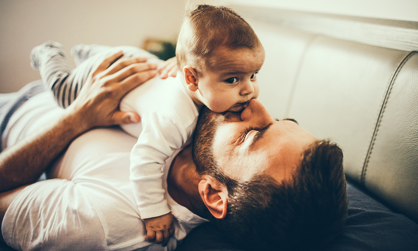 Father playing in bed with his little baby boy