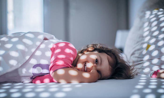 Little girl waking up in bed
