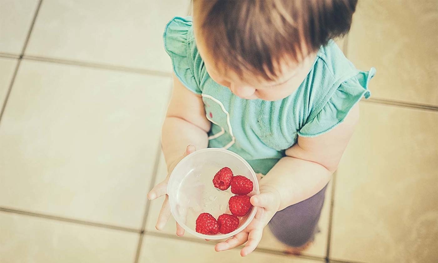 Toddler with raspberries in a bowl
