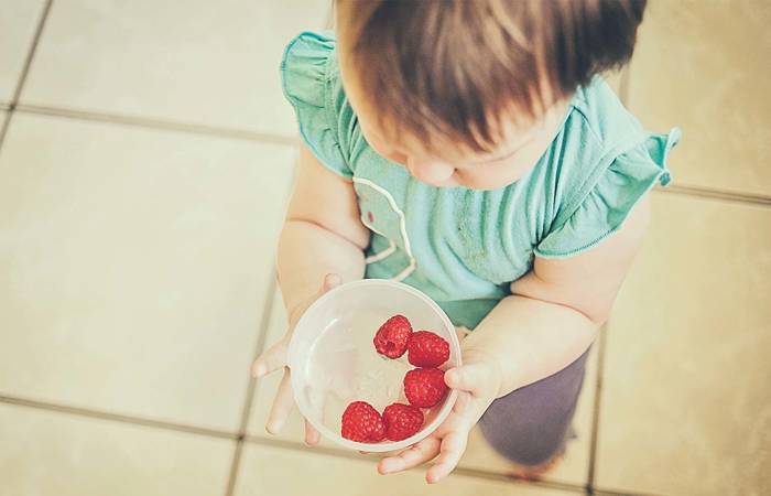 Toddler with raspberries in a bowl