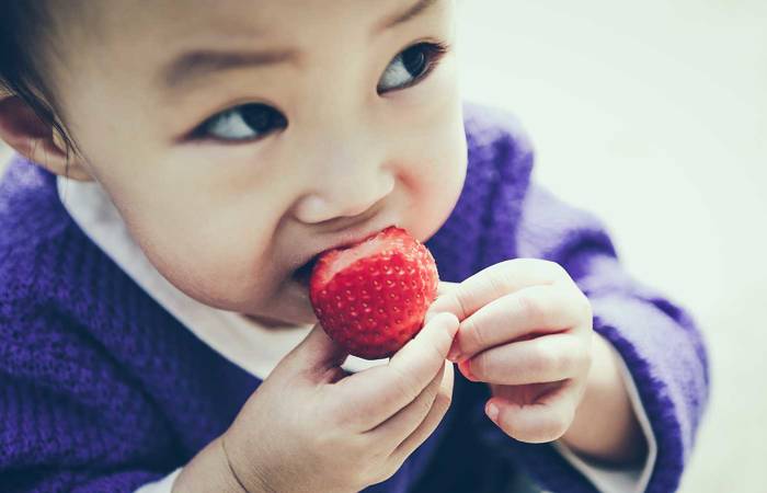 Toddler eating a strawberry