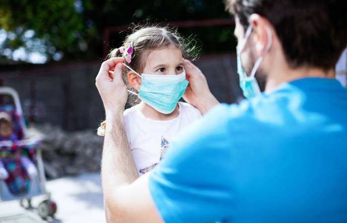 Father applying pollution mask to his daughter.