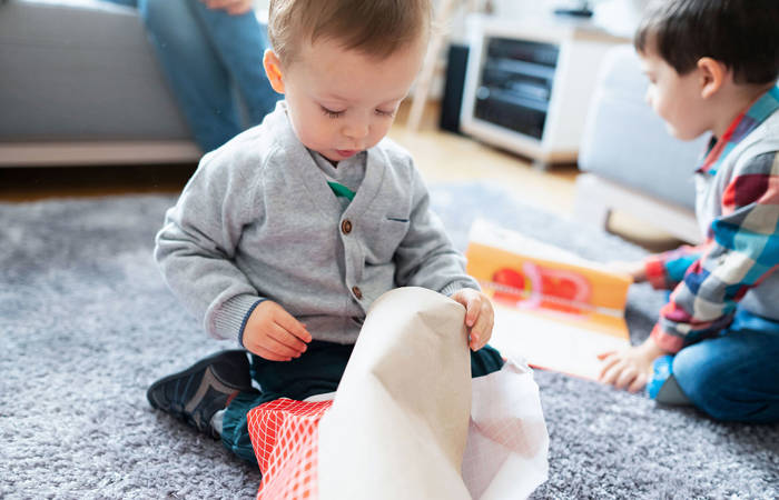 Two boys sitting on the floor and opening presents.