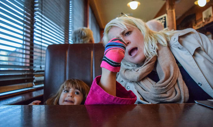 Little girl puts her socked foot on the table at a restaurant