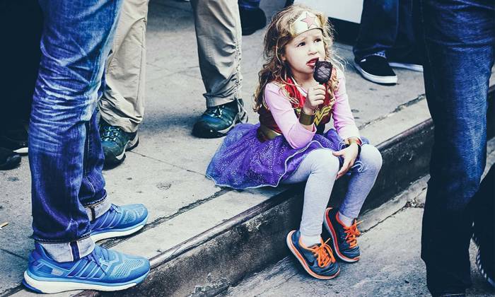 Little girl sitting in the gutter eating ice-cream