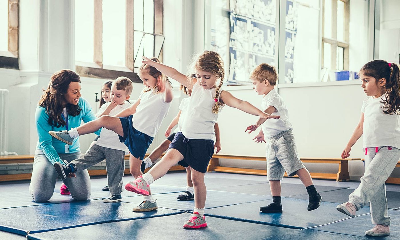 Small children learning to balance encouraged by a teacher
