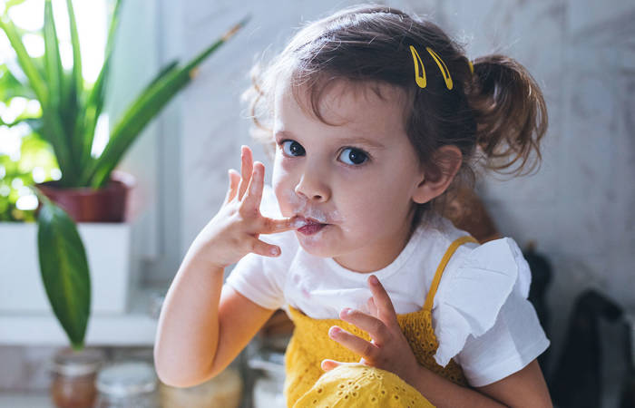 Little girl eating whipped cream with her fingers