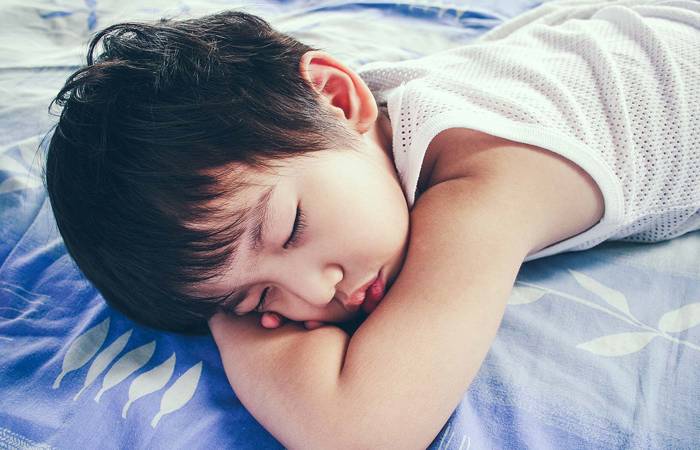 Boy sleeping in bed on blue blanket