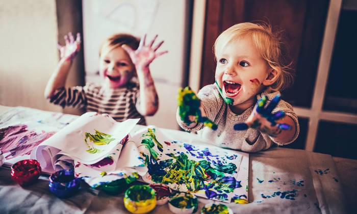 Cheerful children having fun doing finger painting