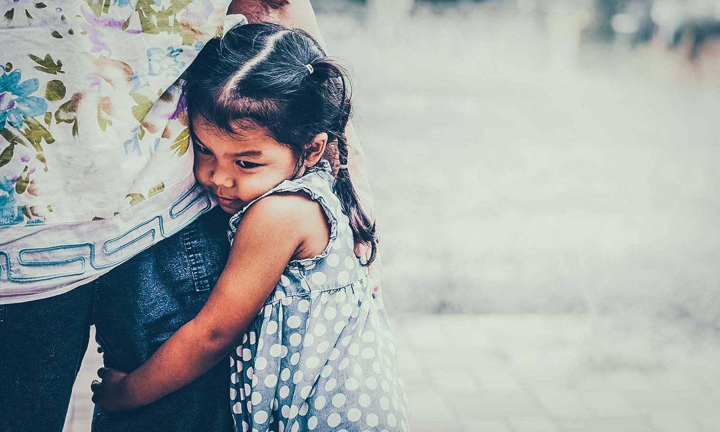Little girl hugging parent's leg