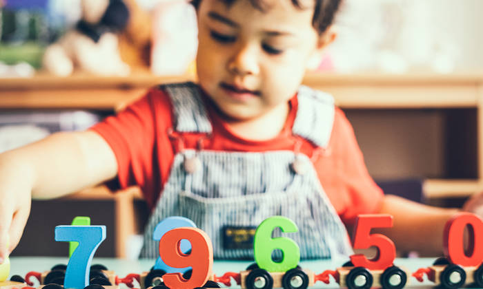 Little boy playing with a mathematics wooden toy