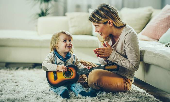Child being praised for learning the guitar