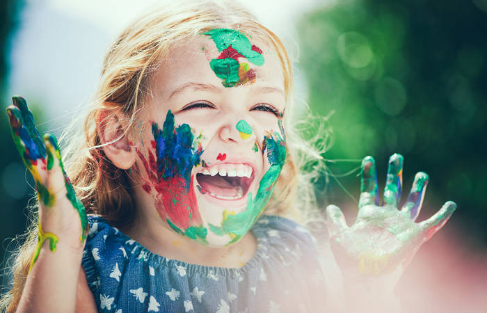 Girl with muticolored paint covering face smiling