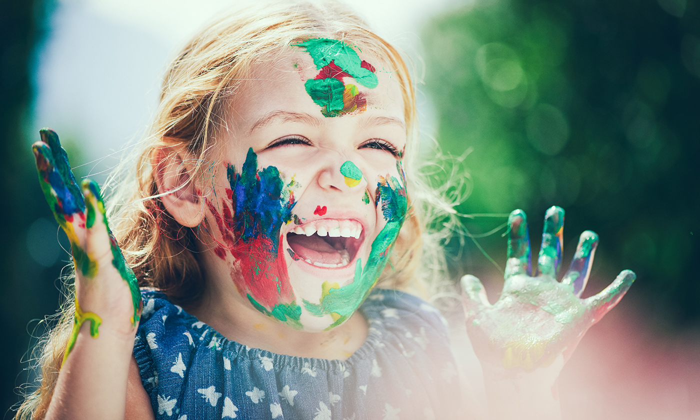 Girl with muticolored paint covering face smiling