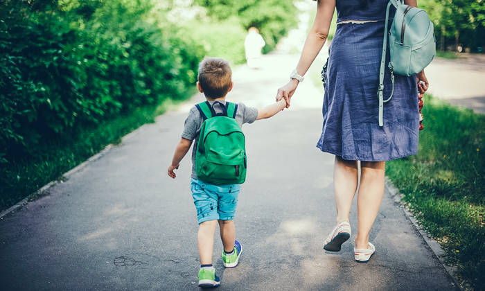 Back view of mother walking down the street with son