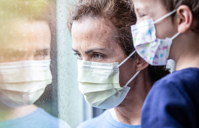 Woman posing with her son, both wearing protective masks