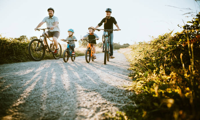 A father and mother ride mountain bikes together with their two small children.