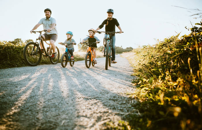 A father and mother ride mountain bikes together with their two small children.