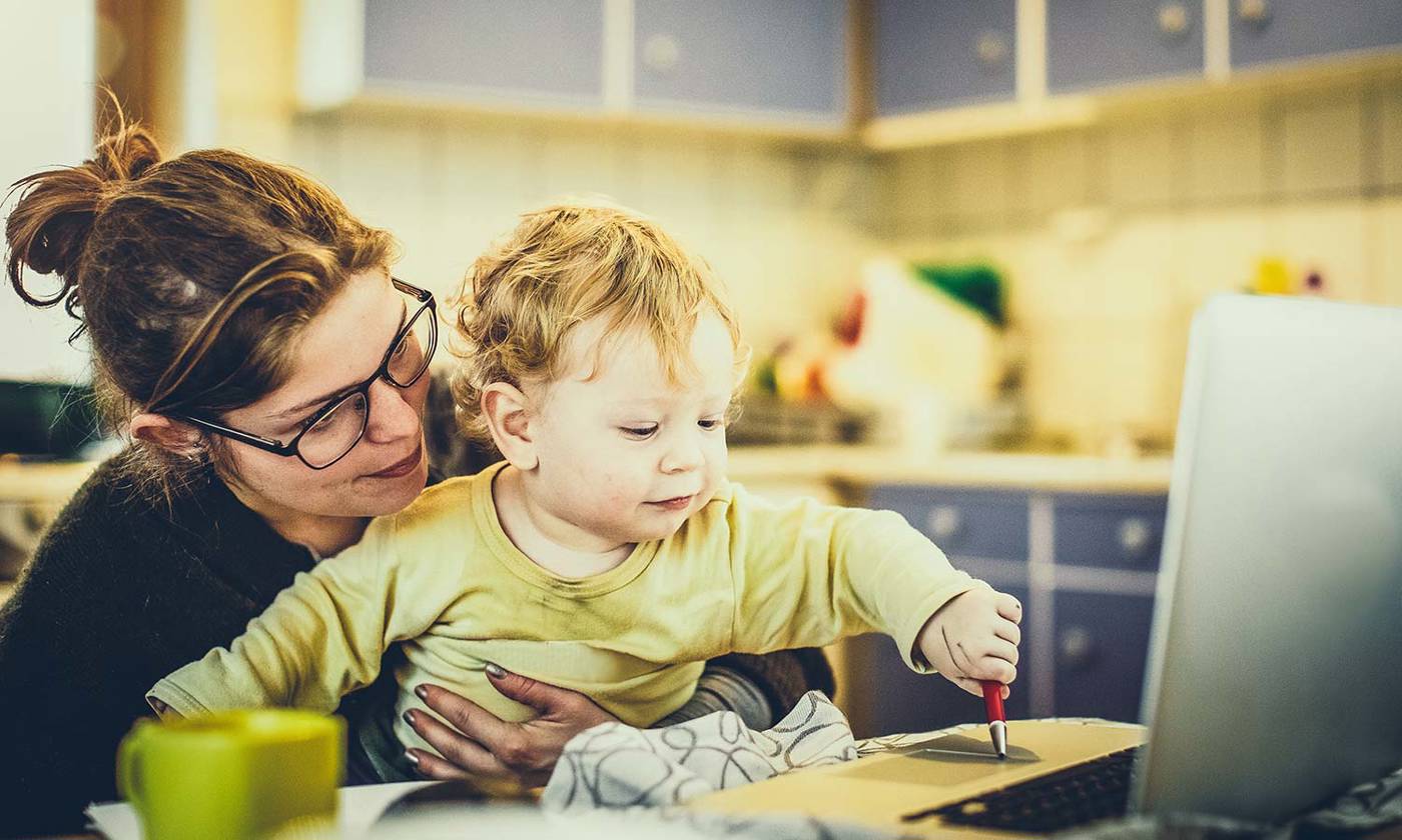 Mother working on laptop with a child