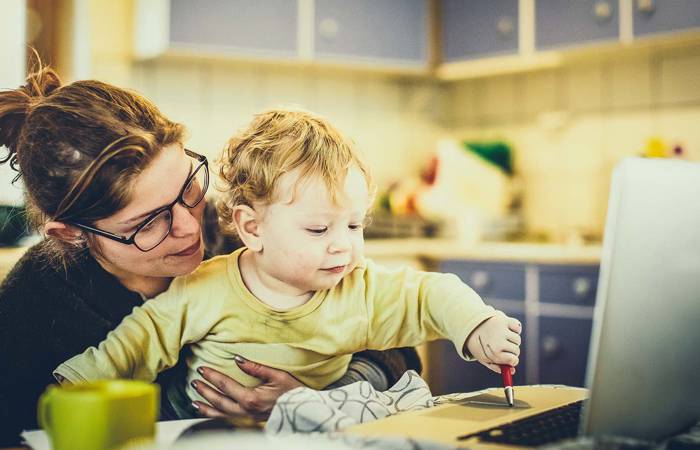 Mother working on laptop with a child