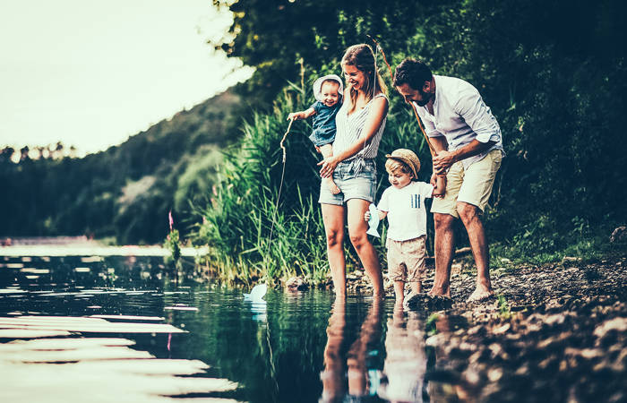 A young family with two toddler children outdoors by the river
