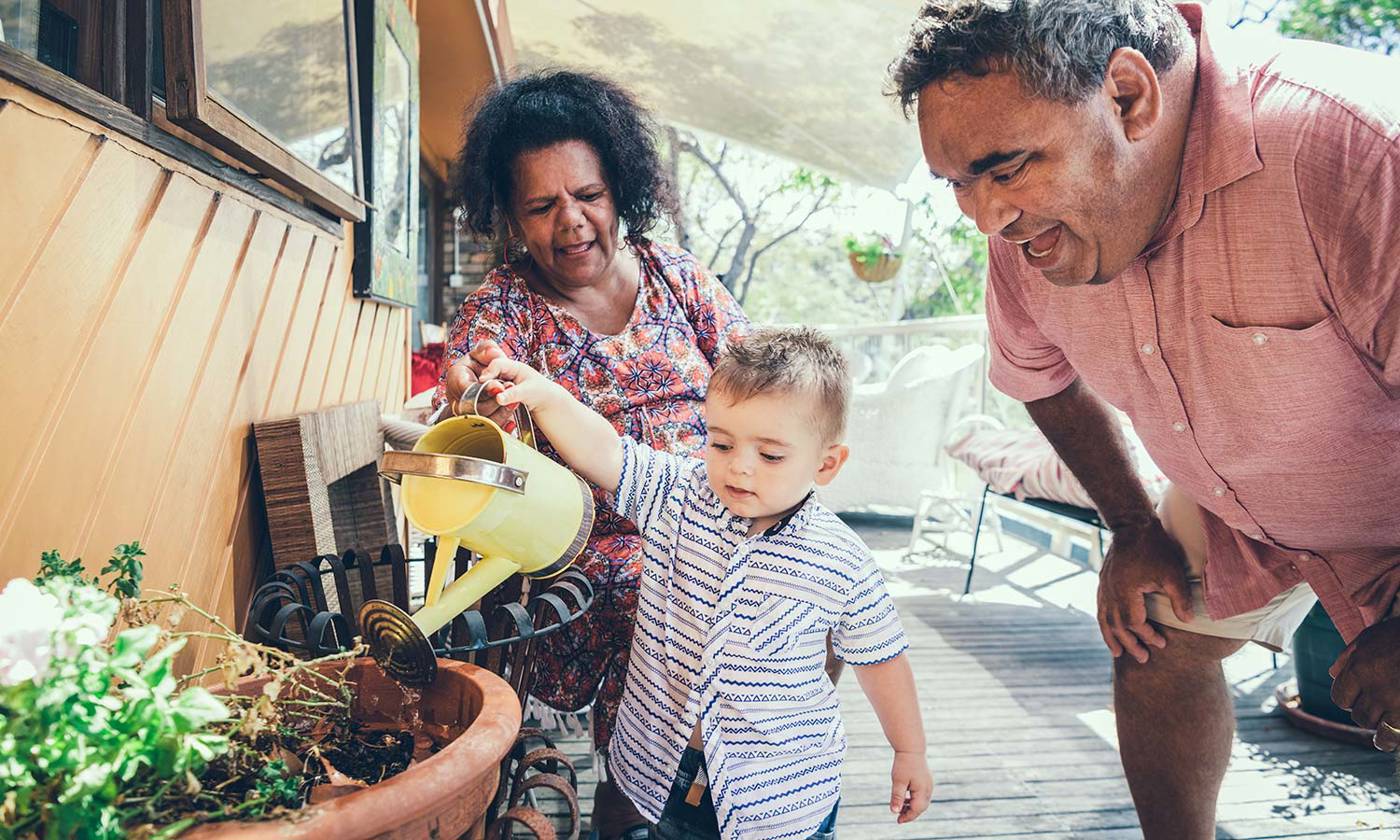 Baby boy watering plants with grandparents