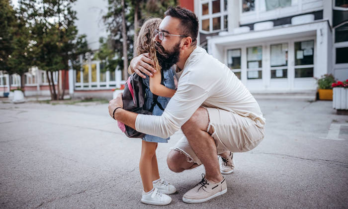 Father hugs daughter as she starts school